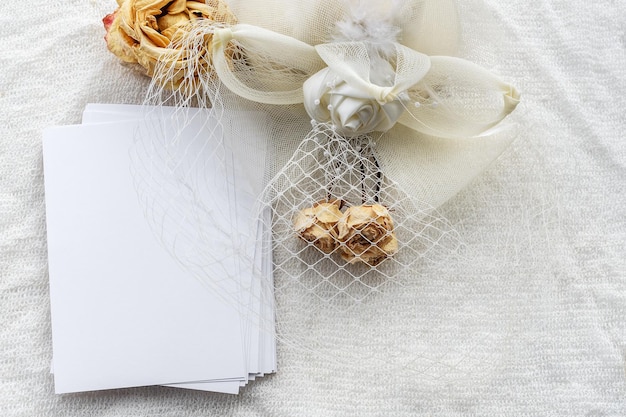 Sfondo femminile alla moda su tessuto bianco fiori un cappello e una cartolina vuota Matrimonio sfondo femminile Vuoto per una cartolina