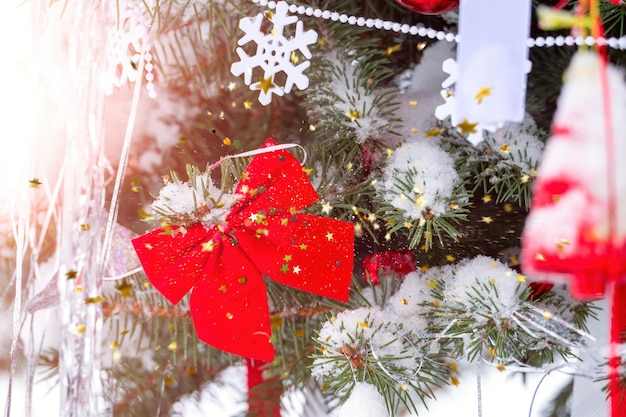 Sfondo festivo Decorazione natalizia con fiocchi di neve rossi di fiocco di Natale in neve e rami di abete innevati