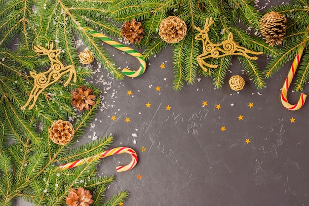 Sfondo festivo natalizio con rami di abete, cervi dorati e coni, decorazione tradizionale - caramello - canna, coriandoli dalle stelle.