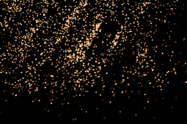 Sfondo festivo nero. Dispersione astratta di scintillii d'oro sul nero. Sfondo di Natale, messa a fuoco selettiva