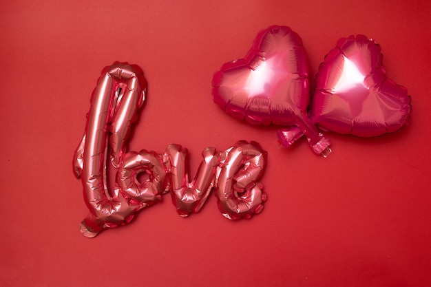 Sfondo festivo per San Valentino da palloncini Foil a forma di cuore e parola d'amore su sfondo rosso