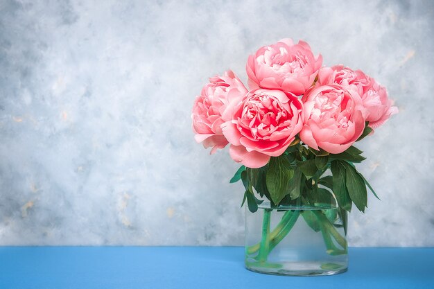 Sfondo floreale artistico. Bellissimo bouquet di fiori di peonie rosa in un vaso di vetro. Grandi boccioli di peonie rosa