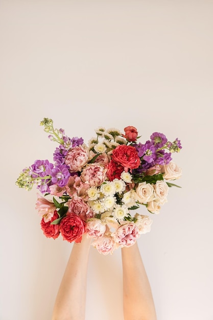 Sfondo floreale estetico astratto Bellissimo bouquet di fiori colorati nelle mani femminili su sfondo bianco Composizione di bellissimi fiori e petali