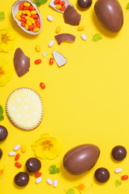 Sfondo giallo di Pasqua con uova di cioccolato, caramelle e spri