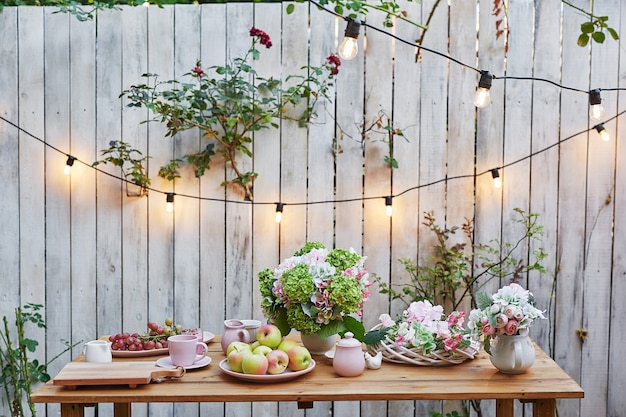 Sfondo giardino estivo. Mazzo delle ortensie dei fiori e della tazza di tè sulla tavola. Buongiorno accogliente. Picnic in natura. Biglietto di auguri per la festa della mamma. Celebrazione