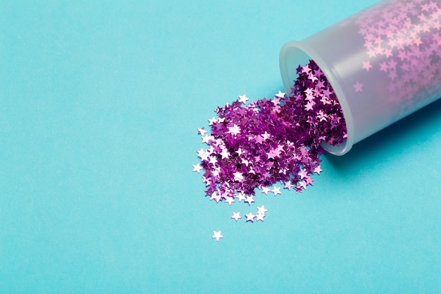 Sfondo glitterato. Stelle glitter viola sparse su uno sfondo colorato. Concetto di vacanza