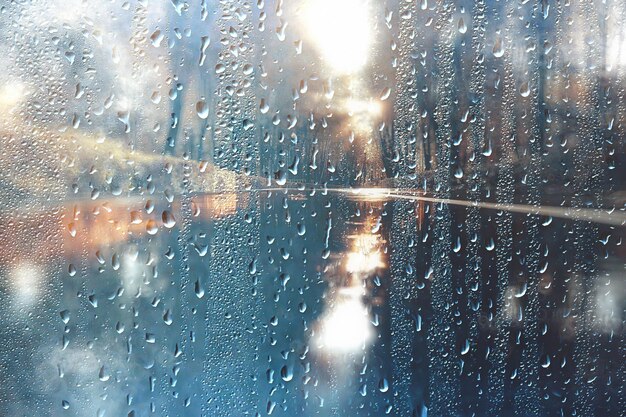 sfondo gocce di vetro bagnato autunno nel parco / vista del paesaggio nel parco autunnale da una finestra bagnata, il concetto di tempo piovoso in una giornata autunnale