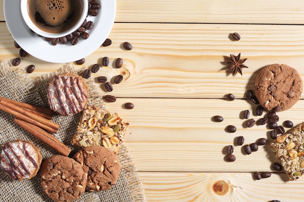 Sfondo in legno con diversi biscotti, tazza di caffè caldo e spazio per il testo. Vista dall'alto