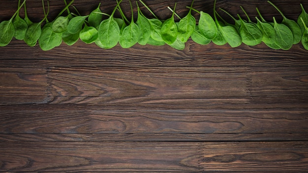 Sfondo in legno con foglie di spinaci baby. Copia spazio. concetto di mangia sano