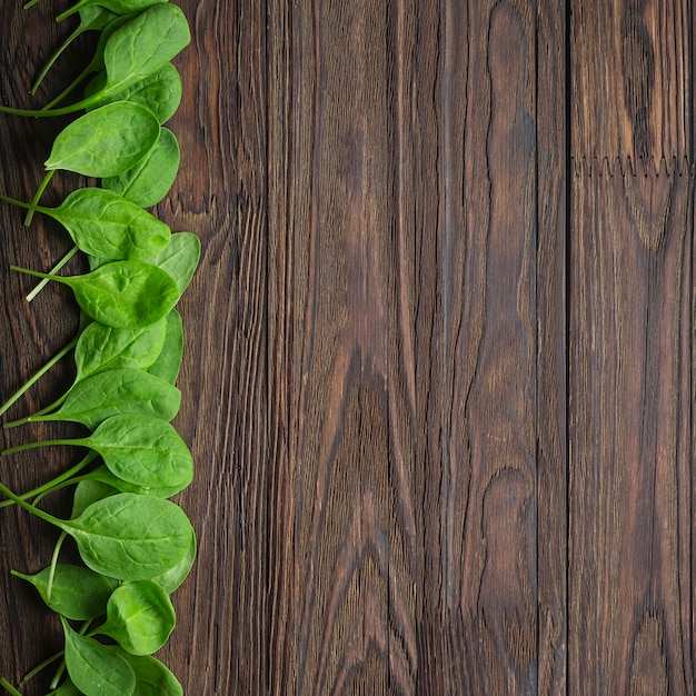 Sfondo in legno con foglie di spinaci baby. Copia spazio. concetto di mangia sano