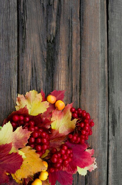 sfondo in legno invecchiato con foglie autunnali luminose e sfondo di bacche con foglie rosse e gialle