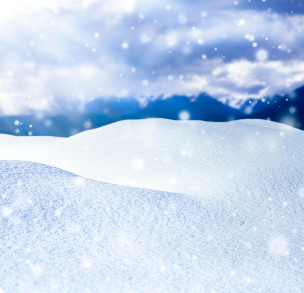 Sfondo invernale con cumuli di neve e montagne blu con fiocchi di neve