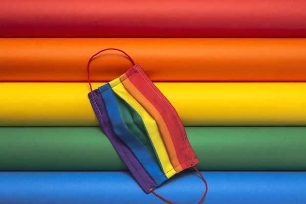 Sfondo LGBT con maschera protettiva color arcobaleno dall'alto. Lay piatto. virus COVID-19