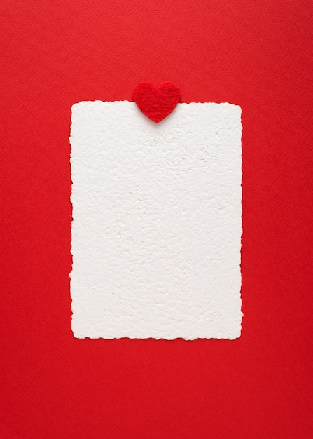 Sfondo minimalista di San Valentino con mockup di carta di carta fatta a mano e cuore rosso. Disposizione piatta con spazio per la copia