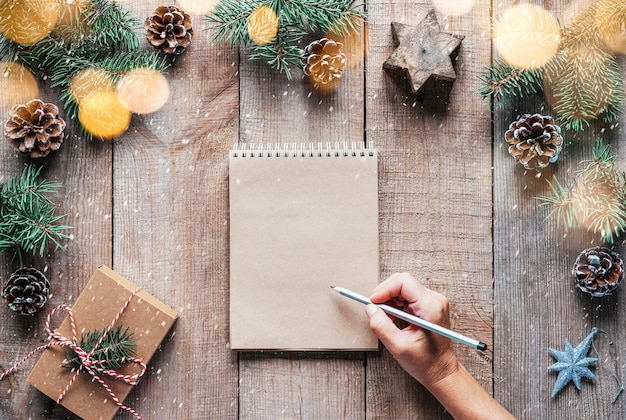 Sfondo natalizio con rami di abete, pigne e scrittura a mano nel blocco note