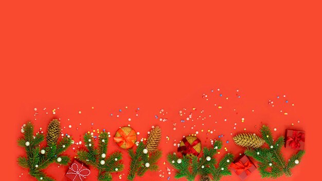 Sfondo natalizio piatto con abete e decorazioni su rosso Spazio libero piatto per banner di design