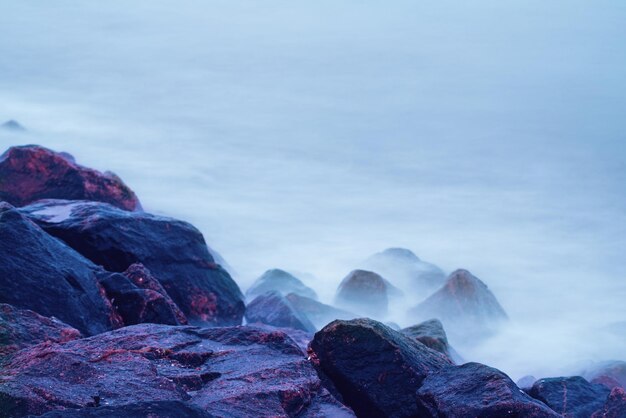 Sfondo naturale da sogno con rocce e onde in riva al mare Esposizione lunga