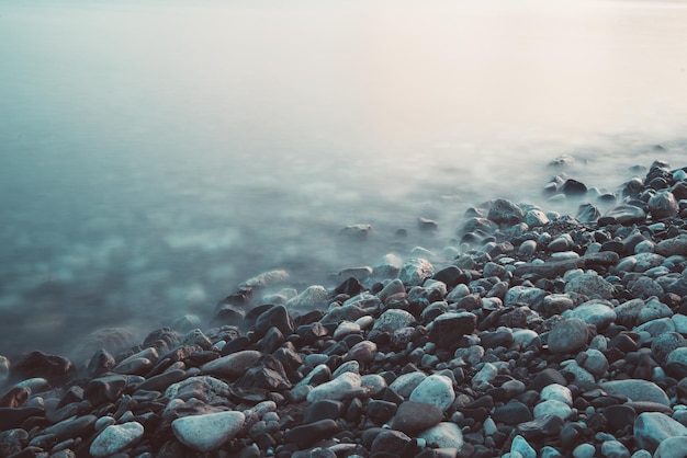 Sfondo naturale da sogno con rocce e onde in riva al mare Esposizione lunga