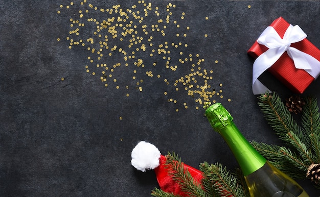 Sfondo nel concetto di Capodanno. Decorazione con abete, regali con una bottiglia di champagne su sfondo nero.