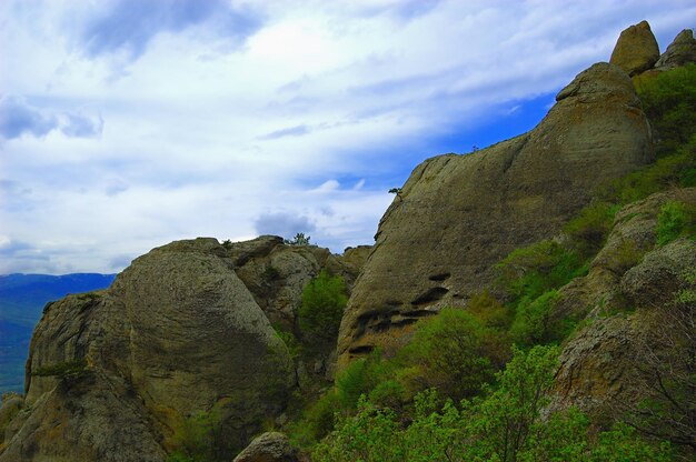 Sfondo orizzontale con un magnifico paesaggio della penisola di Crimea Vista dall'alto delle montagne ricoperte da una vegetazione lussureggiante e delle fitte nuvole sotto le cime Cielo blu chiaro Spazio di copia