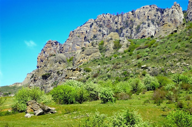 Sfondo orizzontale con un magnifico paesaggio della penisola di Crimea Vista dall'alto delle montagne ricoperte da una vegetazione lussureggiante e delle fitte nuvole sotto le cime Cielo blu chiaro Spazio di copia