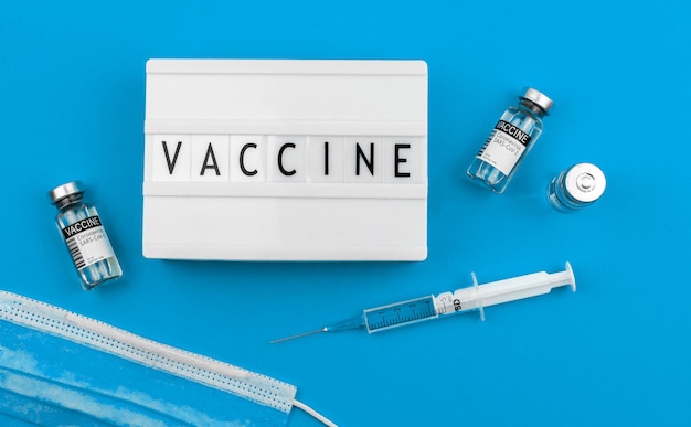 Sfondo parola vaccino, flaconi di vaccino e siringa medica nella tabella, foto di concetto di vaccinazione e assistenza sanitaria