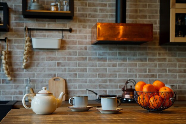 Sfondo per la cerimonia del tè all'interno della zona cucina in una casa accogliente. Gli sfondi della teiera con le tazze sono sul tavolo in attesa del tè con gli ospiti. Concetto di comfort domestico e relax. Copia spazio