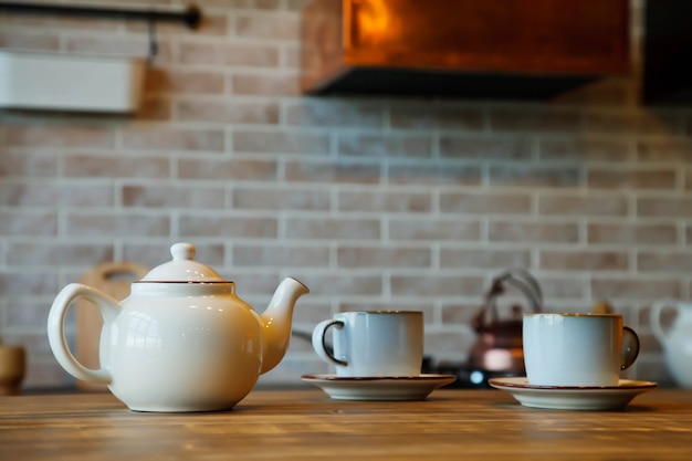 Sfondo per la cerimonia del tè all'interno della zona cucina in una casa accogliente. La teiera con le tazze è sul tavolo in attesa del tè con gli ospiti. Concetto di comfort domestico e relax. Copia spazio