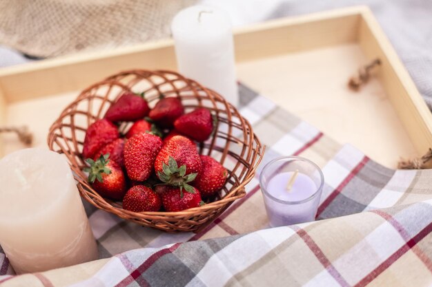 Sfondo picnic estivo Fragole in un cesto di vimini su un vassoio con un tovagliolo a scacchi