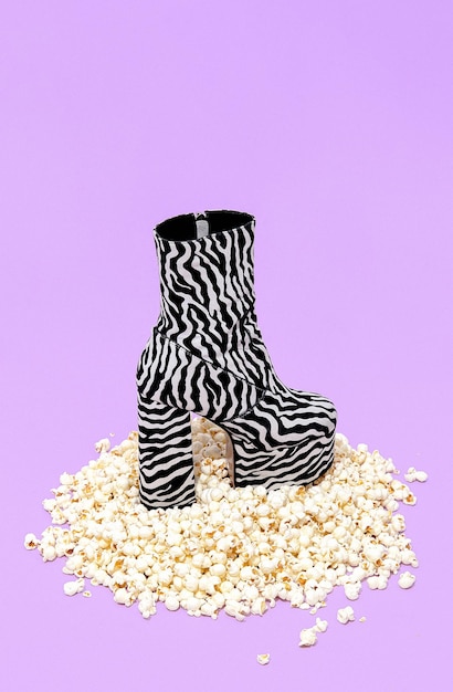 Sfondo popcorn minimo e stivali zebrati alla moda. Disegno di natura morta. Concetto di home cinema alla moda