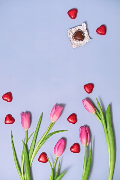 Sfondo primaverile con tulipani e cioccolatini a forma di cuore per la festa della mamma, la festa della donna o il giorno di San Valentino