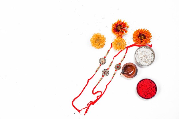 Sfondo Raksha Bandhan con un elegante Rakhi, chicchi di riso e Kumkum su sfondo bianco