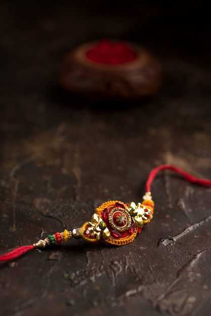 Sfondo Raksha Bandhan con un elegante Rakhi, Chicchi di Riso e Kumkum