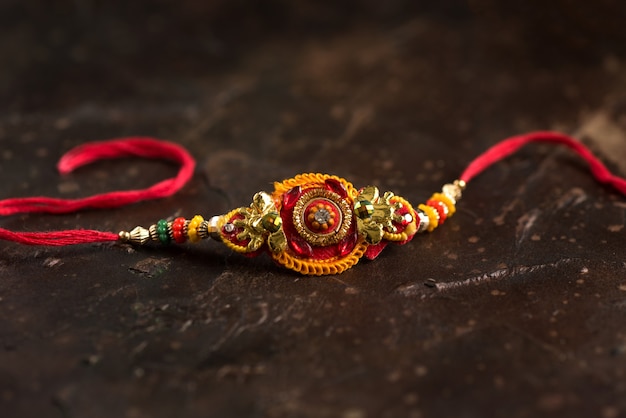 Sfondo Raksha Bandhan con un elegante Rakhi e riso sparso