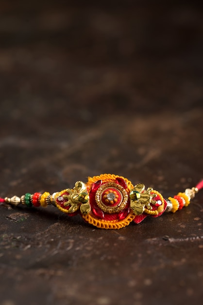 Sfondo Raksha Bandhan con un elegante Rakhi e riso sparso