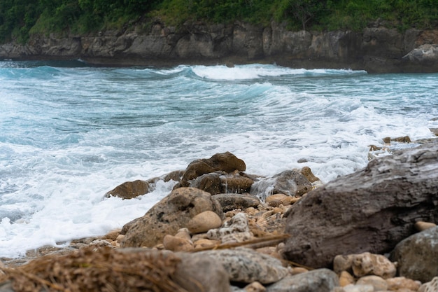 sfondo tropicale, spiaggia con acqua blu, onde che si infrangono sulla pietra