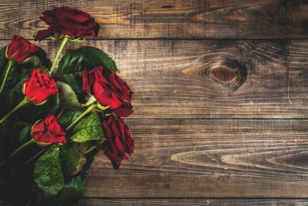 Sfondo vacanza, San Valentino. Bouquet di rose rosse, cravatta con un nastro rosso. Su un tavolo di legno