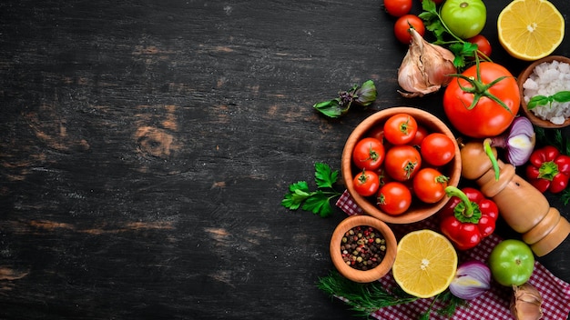 Sfondo vegetale Pomodori freschi paprika cipolle e prezzemolo sul tavolo Vista dall'alto su sfondo nero Spazio libero per il testo