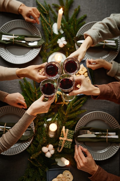 Sfondo vista dall'alto di quattro persone che si godono la cena di Natale insieme e brindano con bicchieri di vino...