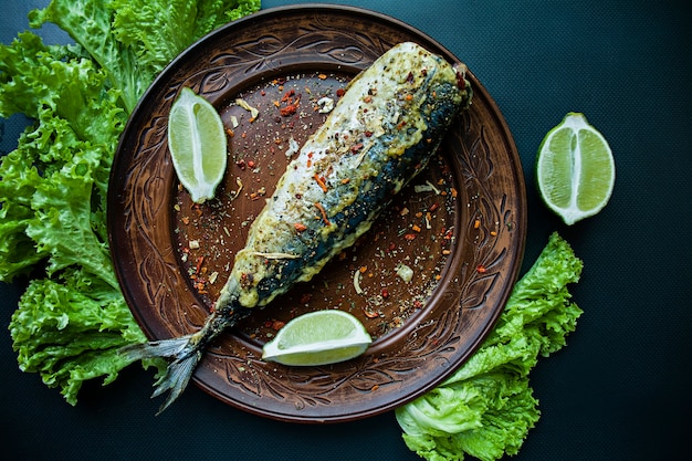 Sgombri fritti su un piatto con condimenti per pesce e verdure. Sfondo scuro Vista dall&#39;alto.