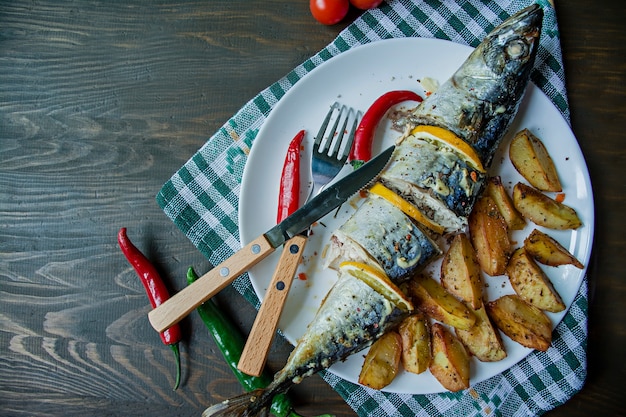 Sgombro al forno con limone e patate al forno su un piatto bianco