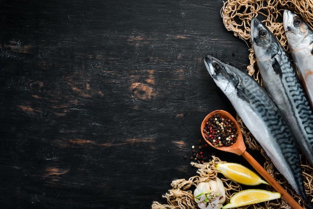 Sgombro crudo di pesce su fondo di legno nero Vista dall'alto Spazio libero per la copia