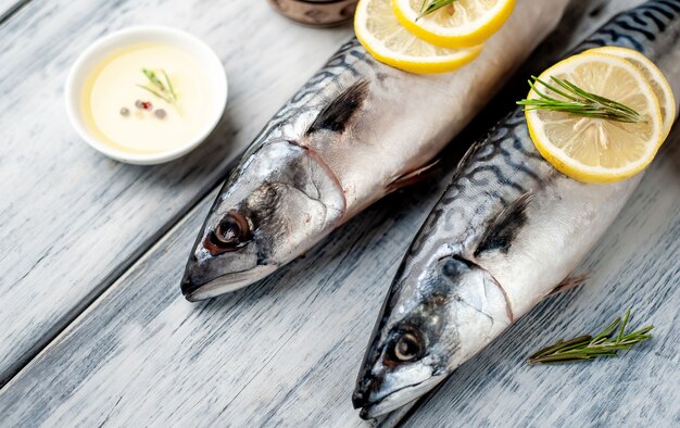 Sgombro fresco e crudo con spezie, pomodori, rosmarino su uno sfondo di legno