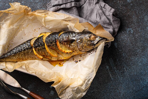 Sgombro intero o pesce scomber con limone ed erbe aromatiche cotto e servito su carta da forno dall'alto, spazio libero per il testo. Pesce sano arrosto delizioso sulla vista superiore del fondo concreto