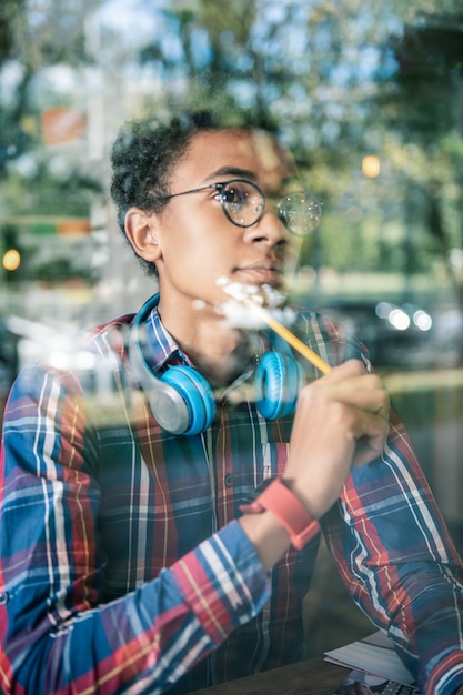 Sguardo premuroso. Piacevole simpatico uomo che si tocca la guancia con una matita mentre cerca nuove idee