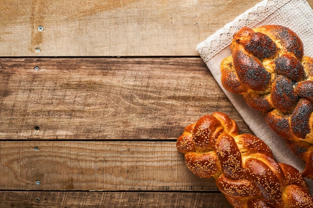 Shabbat Shalom Pane challah con semi di sesamo e semi di papavero su sfondo di legno Pane ebraico tradizionale per Shabbat e vacanze Concetto rustico Spazio di copia Messa a fuoco selettiva