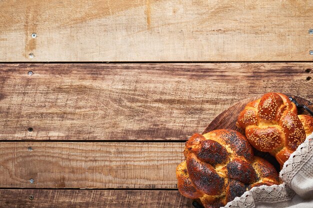 Shabbat Shalom Pane challah con semi di sesamo e semi di papavero su sfondo di legno Pane ebraico tradizionale per Shabbat e vacanze Concetto rustico Spazio di copia Messa a fuoco selettiva