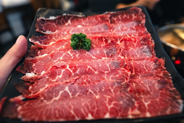 Shabu di manzo affettato in un piatto nero in un ristorante, carne di manzo affettata giapponese