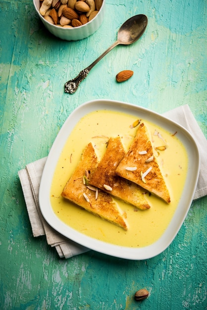 Shahi tukra o tukda o Double ka meetha è un budino di pane dolce indiano di fette di pane fritto imbevute di latte rabbioso o dolce allo zafferano guarnito con frutta secca, messa a fuoco selettiva