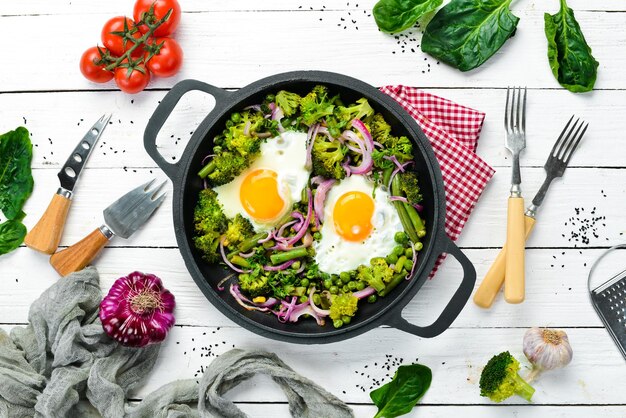 Shakshuka di verdure in padella Uova fritte con verdure broccoli piselli fagioli cipolle Vista dall'alto Spazio libero per il testo